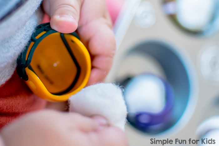 Quick and simple sensory play for toddlers with mini football helmets and cotton balls in a muffin tin!