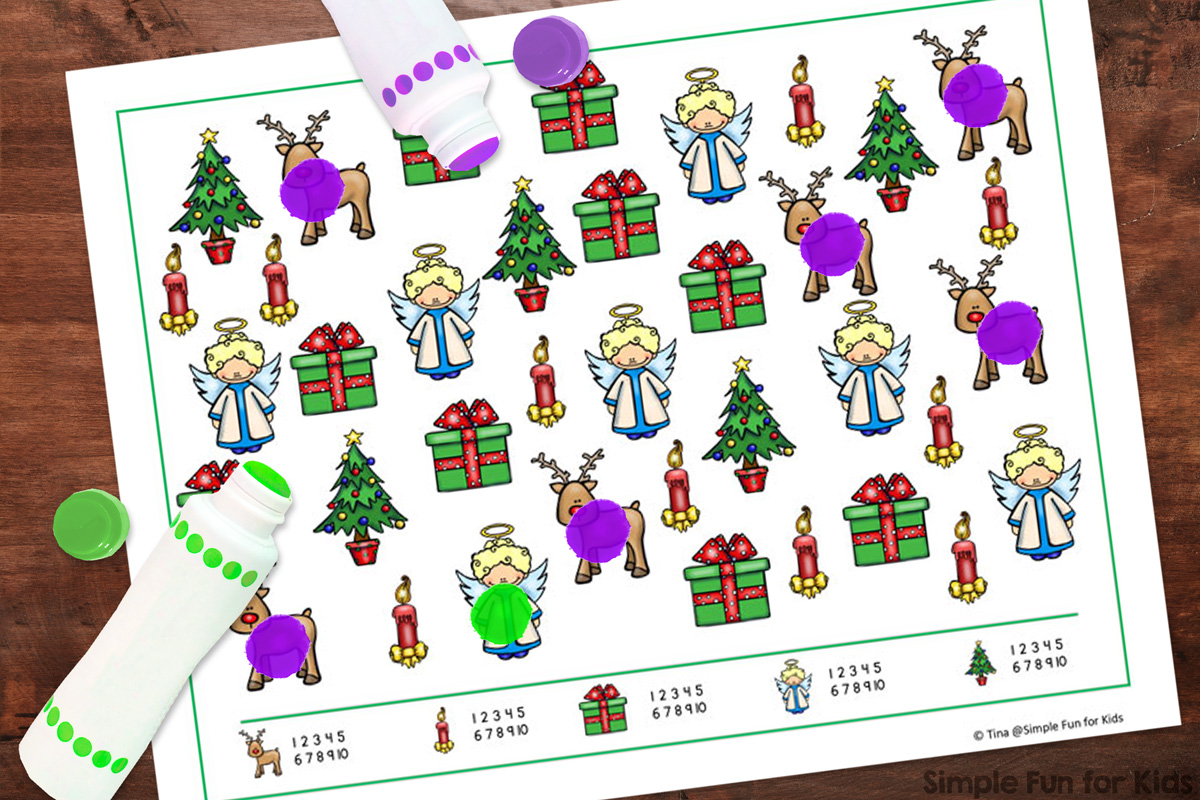 Picture of the Christmas I Spy game on top of a wooden desk with a green and a purple dot marker and dots on some of the images.