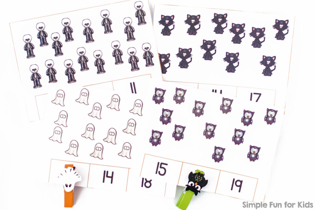 Four Halloween counting clip cards with clothespins marking the correct numbers on top of a white desk.